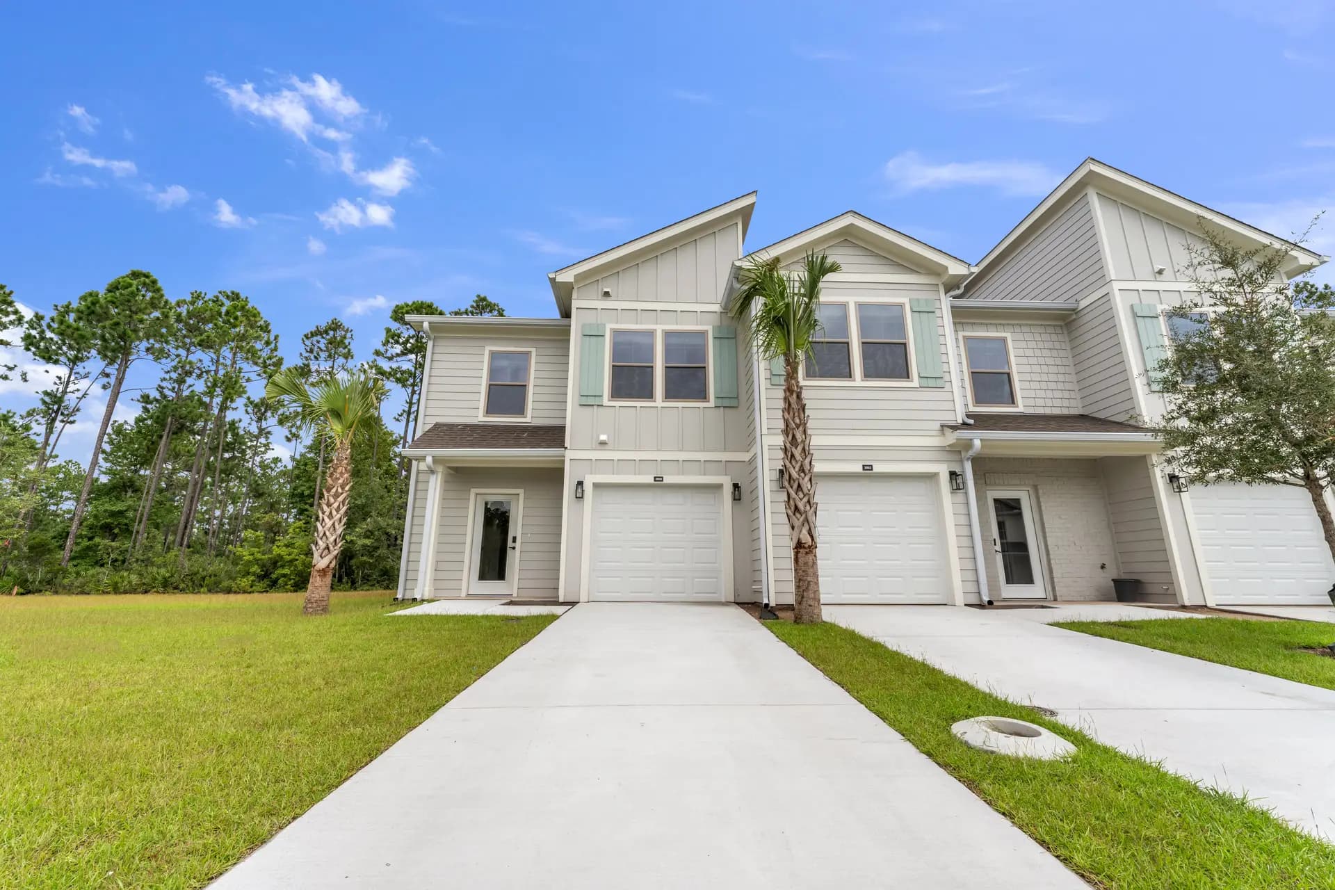 Townhomes with seafoam shutters and single-car garages at Pointe Villas Bergen Woods
