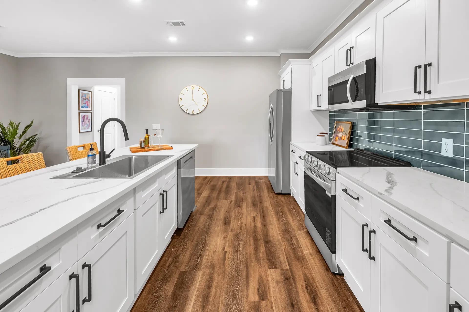 A Bergen Woods kitchen with white shaker cabinets, quartz island, and teal subway tile backsplash
