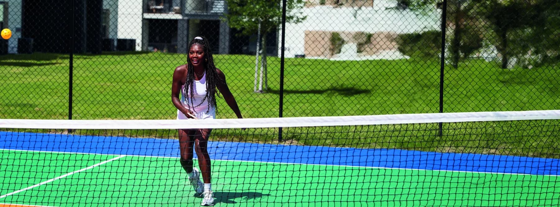 A resident mid-rally at the net on the community pickleball court