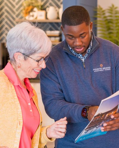Older woman and younger man review a brochure together in a brightly lit, modern indoor setting.